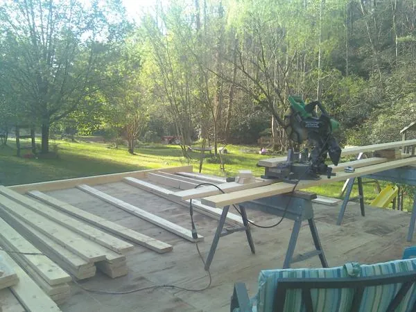 Miter saw and framing lumber on a deck under construction in Williams